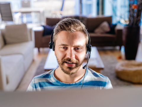 Man working from home on computer, wearing headset
